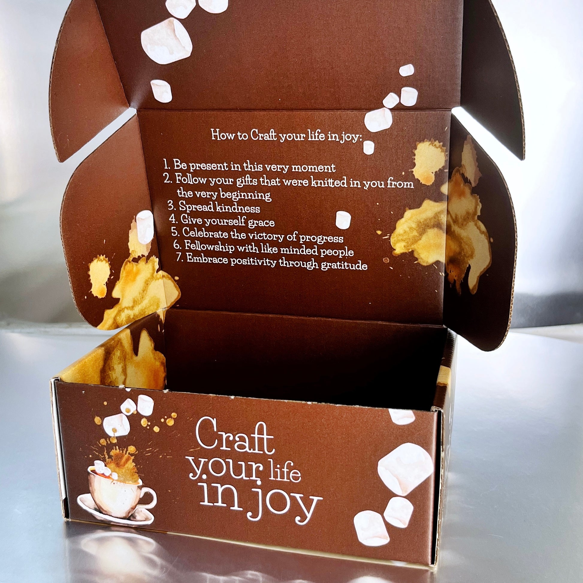 Inside of the box for the hot chocolate experience with the logo of chef farrell drinking cocoa and the words craft your life in joy on the outside