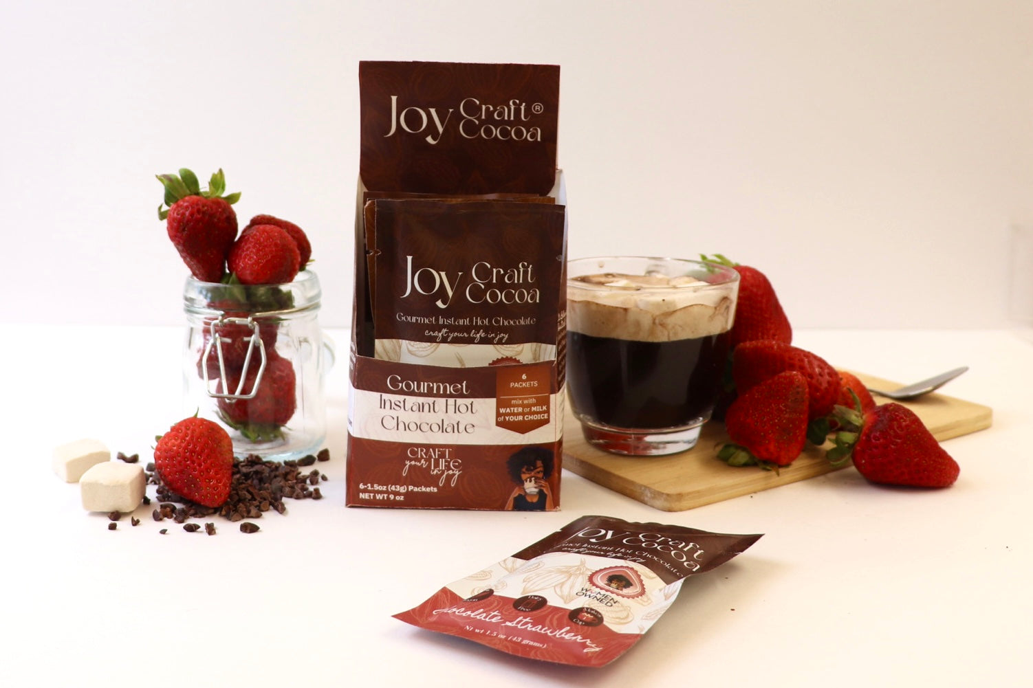 joy craft cocoa box with strawberries on a cutting board and in a jar with a cup of hot chocolate